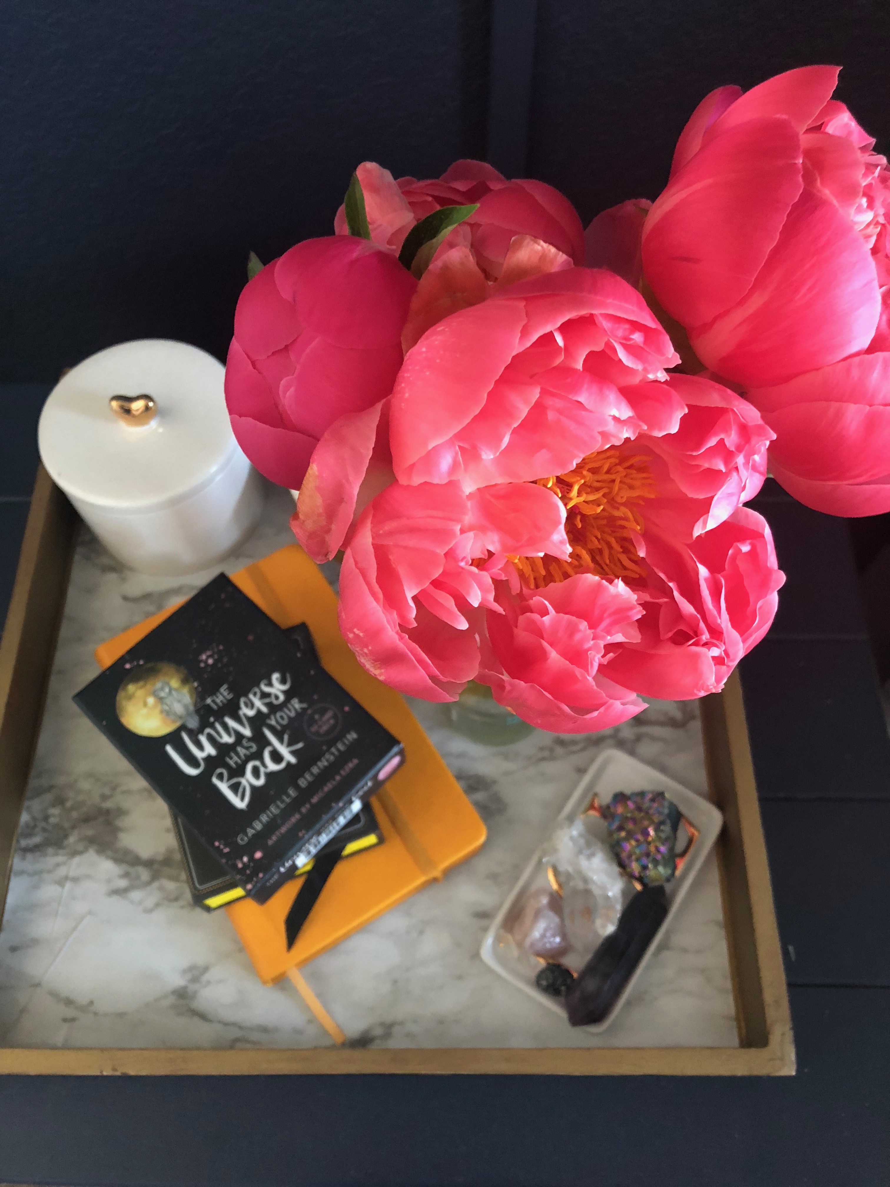 Styled tray detail with peonies, candle, and books
