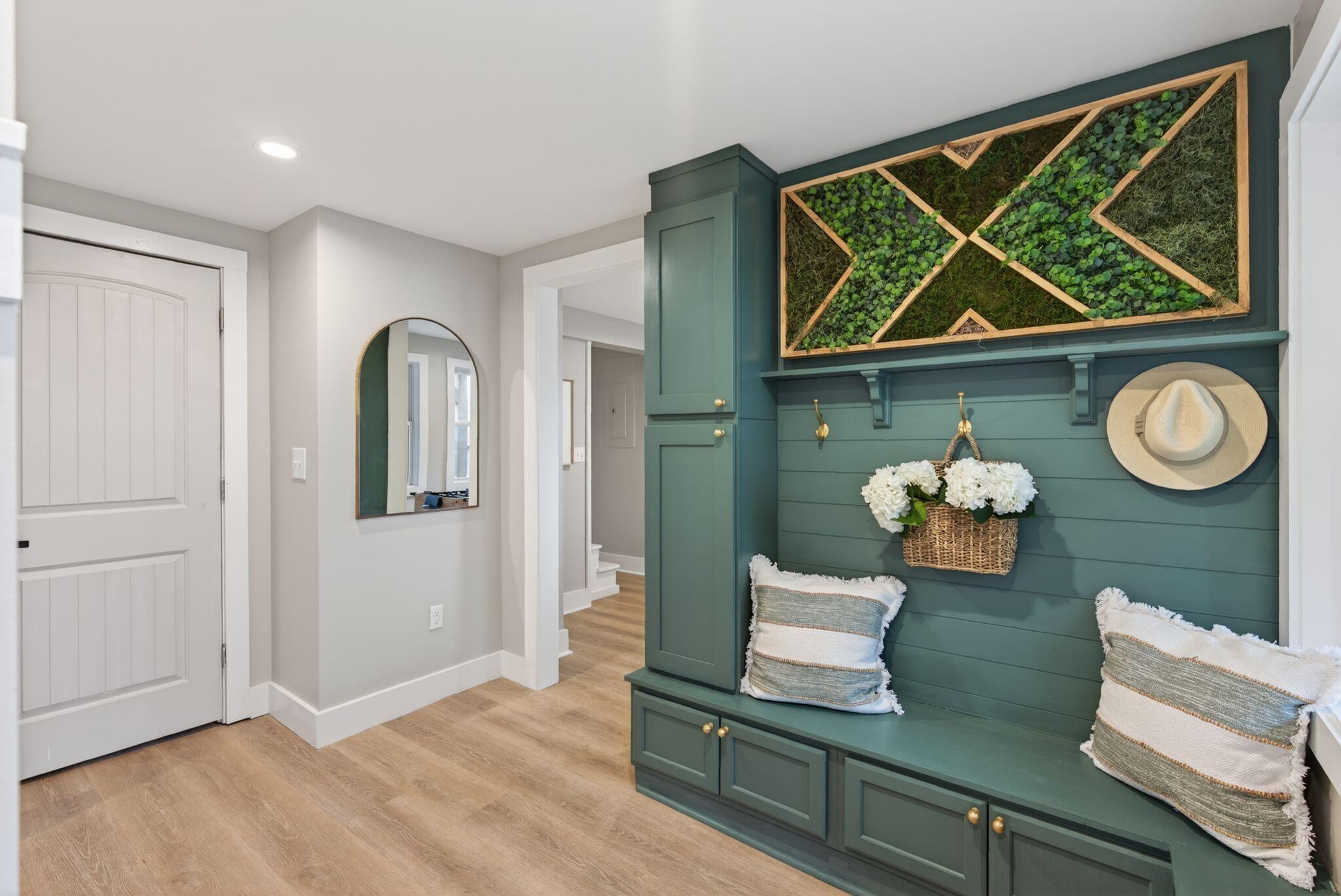 Green mudroom with built-in bench and brass details