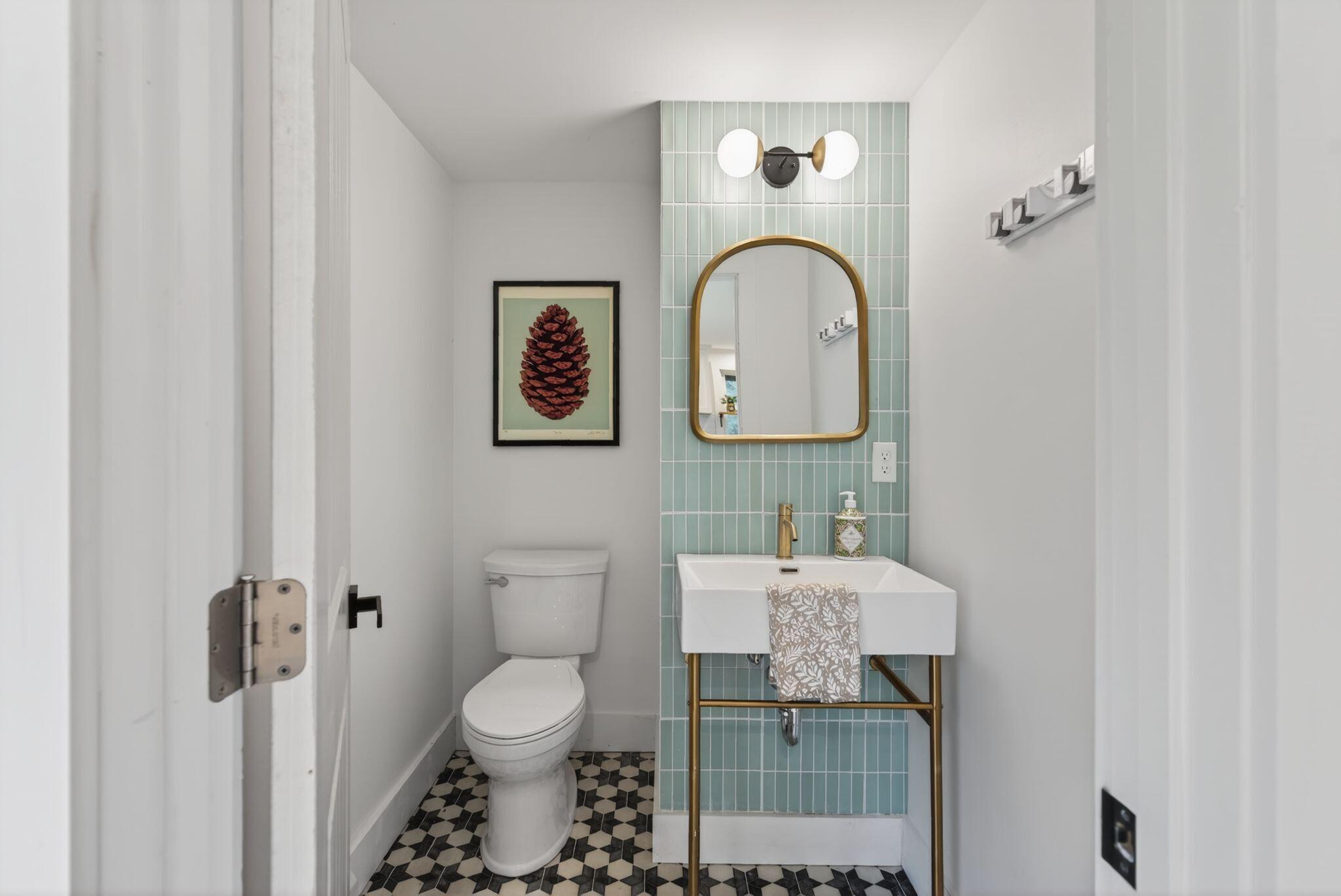 Powder room with teal tile and gold mirror